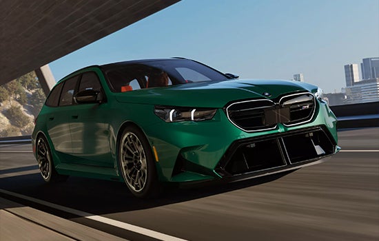 Green BMW M5 Touring driving on a city road. | Taylor BMW in Evans GA